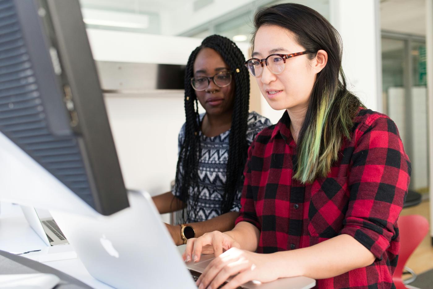 Women wearing red and black checkered blouse using macbook
