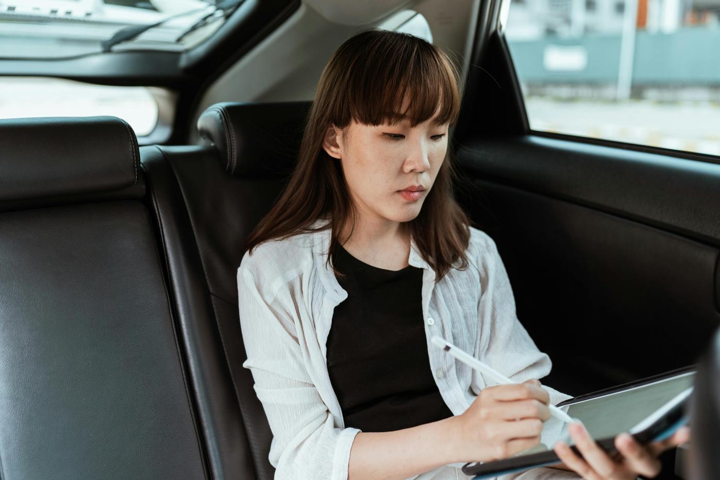 Focused woman using tabler and stylus in car